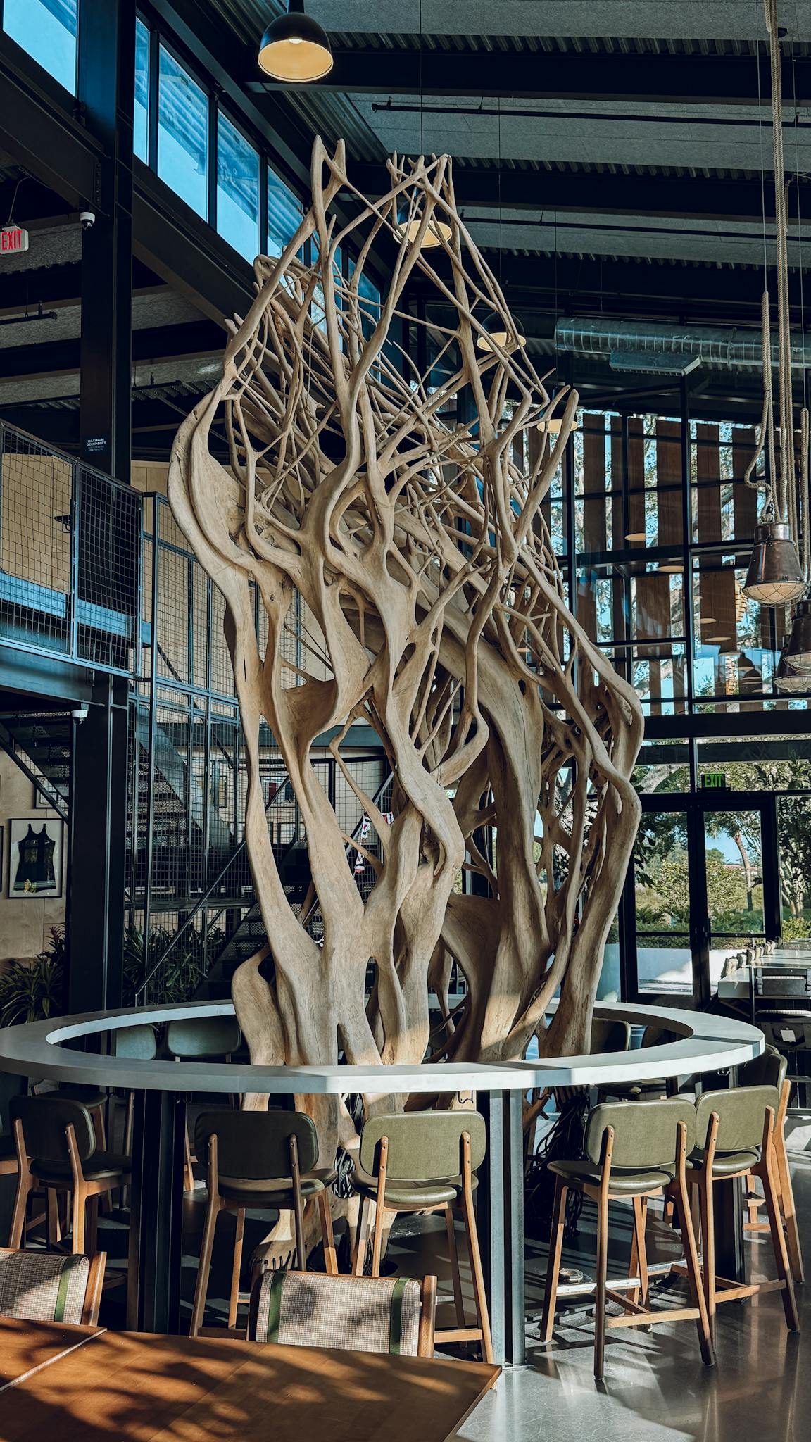 Unique modern sculpture inside a stylish, light-filled restaurant with large windows.